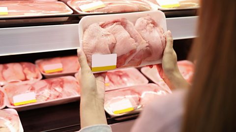 Woman looking at chicken pieces in the supermarket