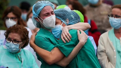 Susana Vera/Reuters Health workers embrace following the death of a colleague in Spain (Credit: Susana Vera/Reuters)