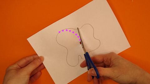 Pink dots show the path scissors should cut to reach a curvy shape on a piece of paper