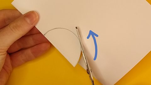 Scissors cutting halfway along a semi circle on folded paper