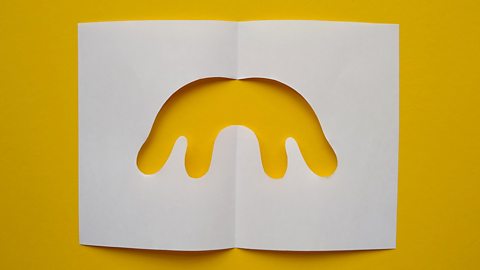 An unfolded piece of paper with a symmetrical, organic-shaped hole in the middle