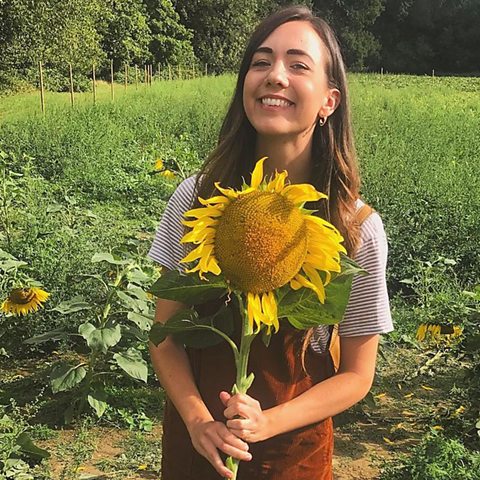 Natalie holding a massive sunflower in a field