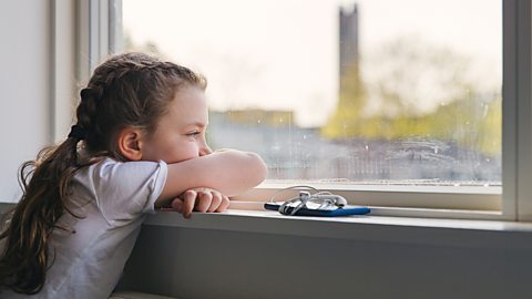 Girl looks forlornly out the window