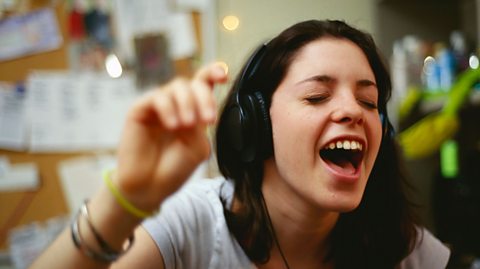 Girl singing to music, she is wearing headphones.