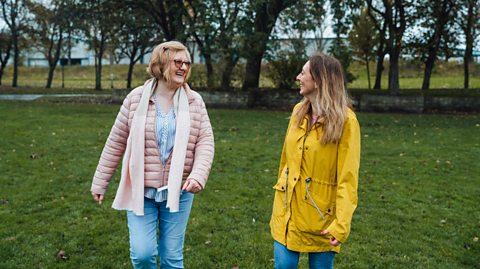 Two women chatting on a walk through the park.