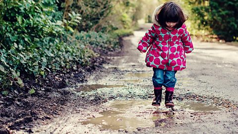 A little girl jumping in a puddle.