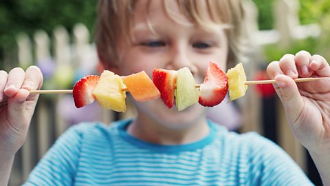 A boy with a fruit kebab