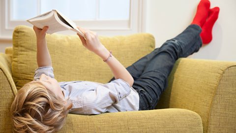 A boy led down reading a book