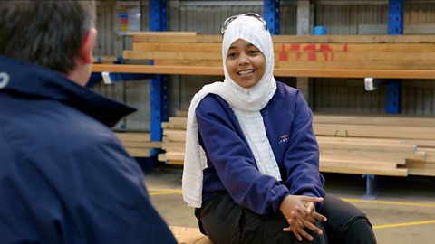 Layla is sitting down in the workshop talking to Norman about job opportunities.