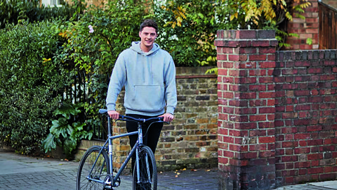 Dr Alex George pushing a bicycle