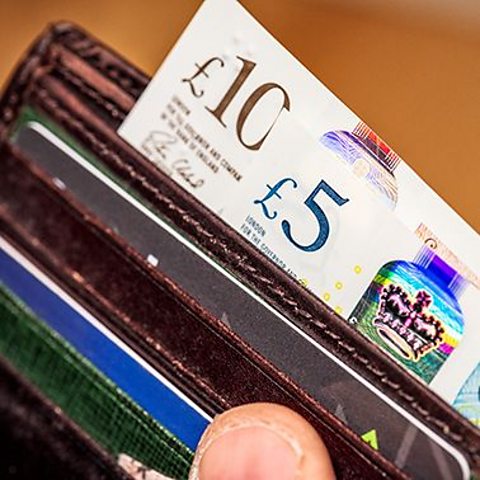 photograph of wallet with bank cards, credit cards and a five pound and ten pound note.