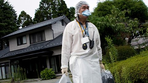 A man leaves his home in Fukushima, wearing protective gear to protect from radiation