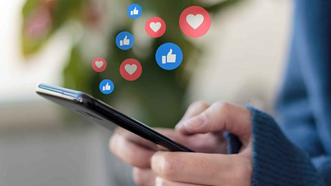 A pair of hands holding a mobile phone, little 'likes' and 'hearts' are flowing up from the phone screen into the air.