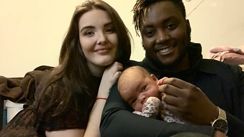 Mhairi and Ndaba with their newborn baby, Delilah, posing for a photograph