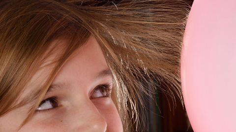 A child's hair sticking to a balloon because of static electricity