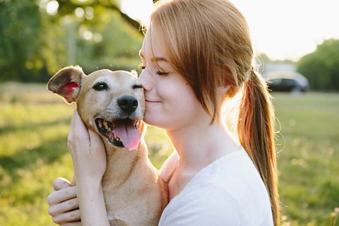 Teenage girl hugs her small mixed-breed dog