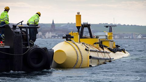 Two workers wearing high-vis are testing wave and tide power machines in Orkney Scotland