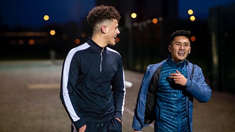 Two lads walking and talking after a football match