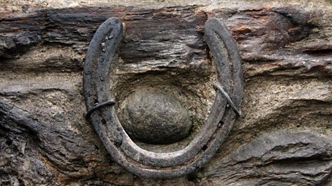 A close up photograph of an old horseshoe nailed into a wall