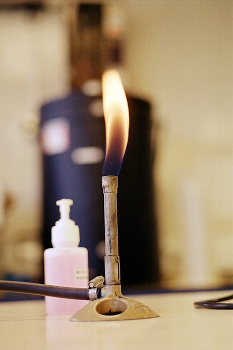 A Bunsen burner with flame.