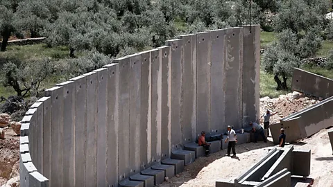 Thomas Coex/Getty Images Concrete builds, but it can also divide. A controversial barrier in the town of Beit Jala in the West Bank (Credit: Thomas Coex/Getty Images)