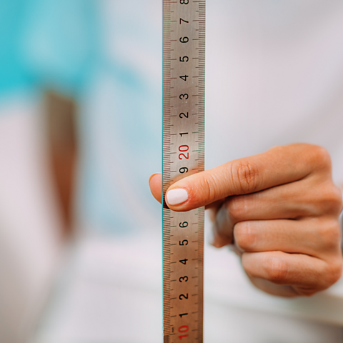 A person holding a ruler halfway along its length