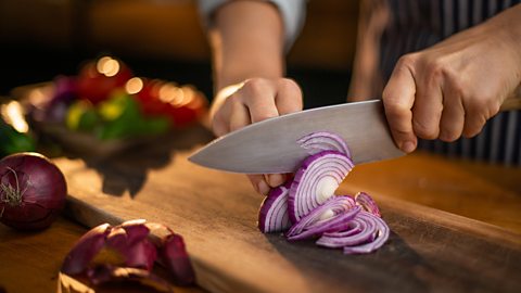 Knife cutting a red onion