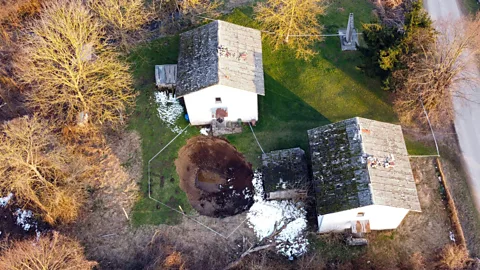 AFP/Getty Images Some of the sinkholes opened up alarmingly close to houses and now scientists hope to find out which areas are safe (Credit: AFP/Getty Images)