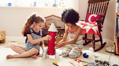 Two girls building a toy rocket