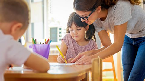 A child colouring in with help from an adult