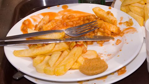 A plate with leftover chips and beans on it