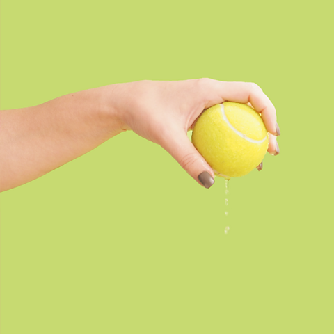 A hand holding a tennis ball ready to drop it.