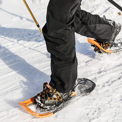A photo of a person wearing snowshoes, walking on snow.