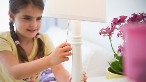 A girl switches a lamp off