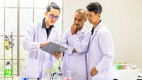 Three scientists looking at results of scientific data on a clip-board.