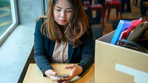 Getty A woman who has resigned sits looking at her phone