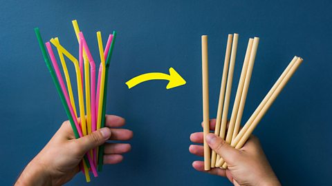 One hand holds plastic straws while another holds bamboo straws