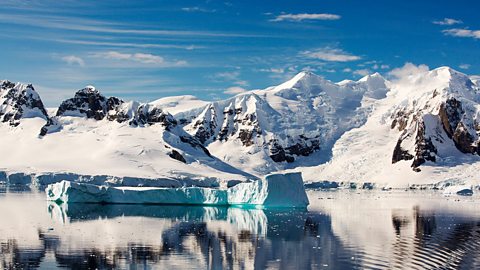 An Antarctic scene with snowy hills, icy water and floating ice.