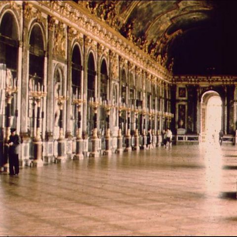 A photograph of the Hall of Mirrors at the Palace of Versailles, with arched floor to ceiling mirrors stretching down the left hand side of the room