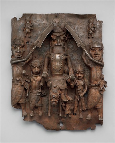 A bronze from Benin depicting one large figure in the middle, with other smaller ones around it. 