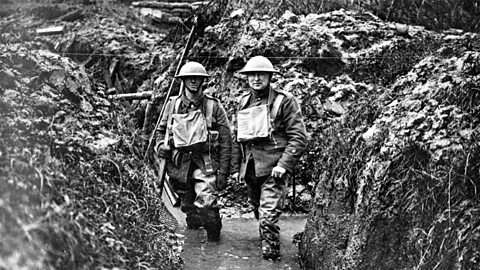 Two British soldiers stand side by side in a flooded trench.