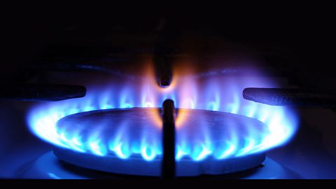 Natural gas burning with a blue and orange flame on a hob