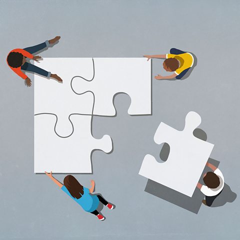 Four people putting four jigsaw pieces together. 