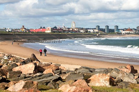 People walking along Aberdeen beach on a cloudy day