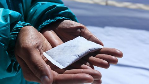 A pair of open palms holding a packet of something