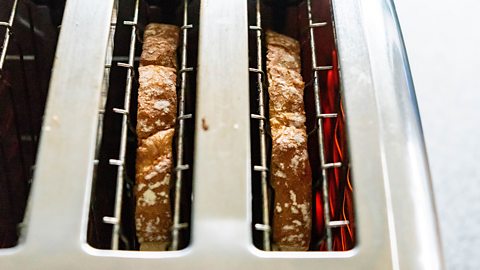 A bird's eye view of two slices of brown bread inside a toaster.