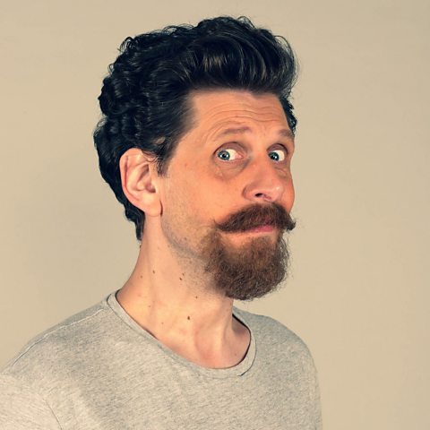 A headshot of Laurence Rickard, against a beige background and wearing a pale grey top.