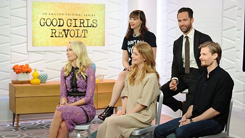 Three actresses and two actors are interviewed sitting on chairs in front of a pale yellow sign, which reads Good Girls Revolt.