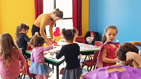 Children doing arts and crafts with an adult at nursery.