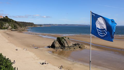 A view of North Beach, Tenby in 2019, with the Blue Flag for cleanliness in the foreground.